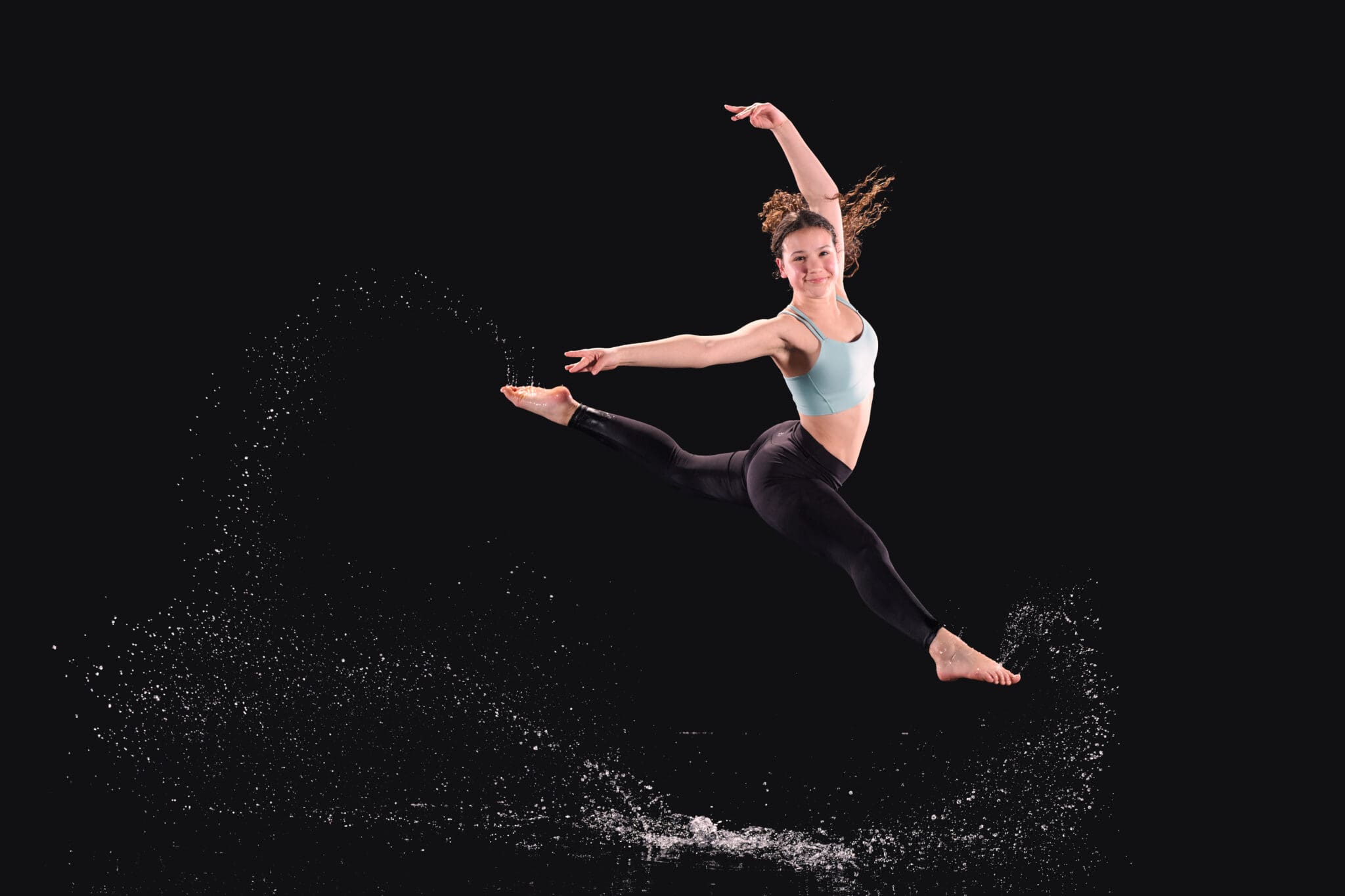 Dancer leaping during dramatic indoor rain session