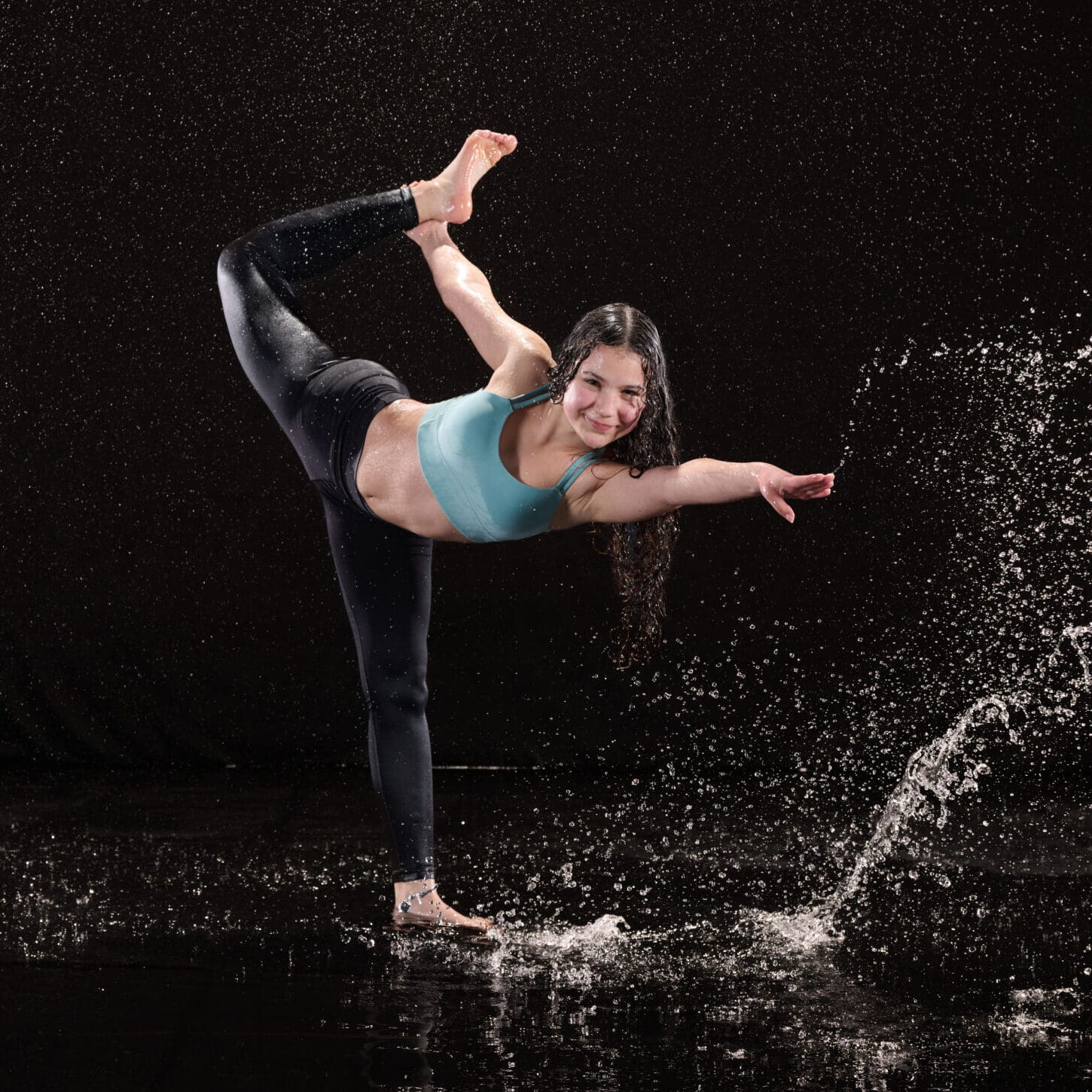 Dancer posing under studio rain with professional lighting